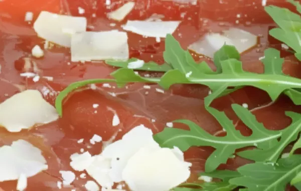 Zartes Rindfleisch, frischer Rucola und würziger Parmesan vereinen sich zu einem köstlichen Carpaccio.