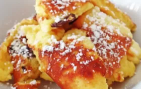 Ein klassisches österreichisches Rezept für luftigen Kaiserschmarrn mit Rosinen, serviert mit Puderzucker und Apfelmus.